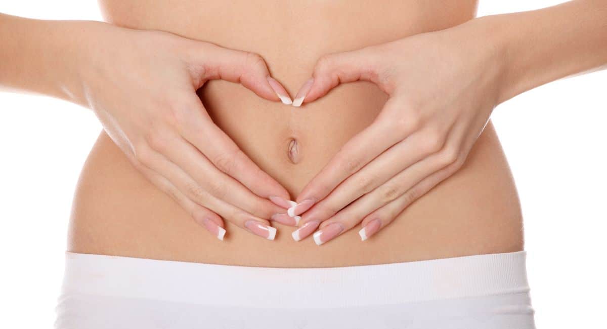 woman using her hands to create the shape of a heart on her stomach.