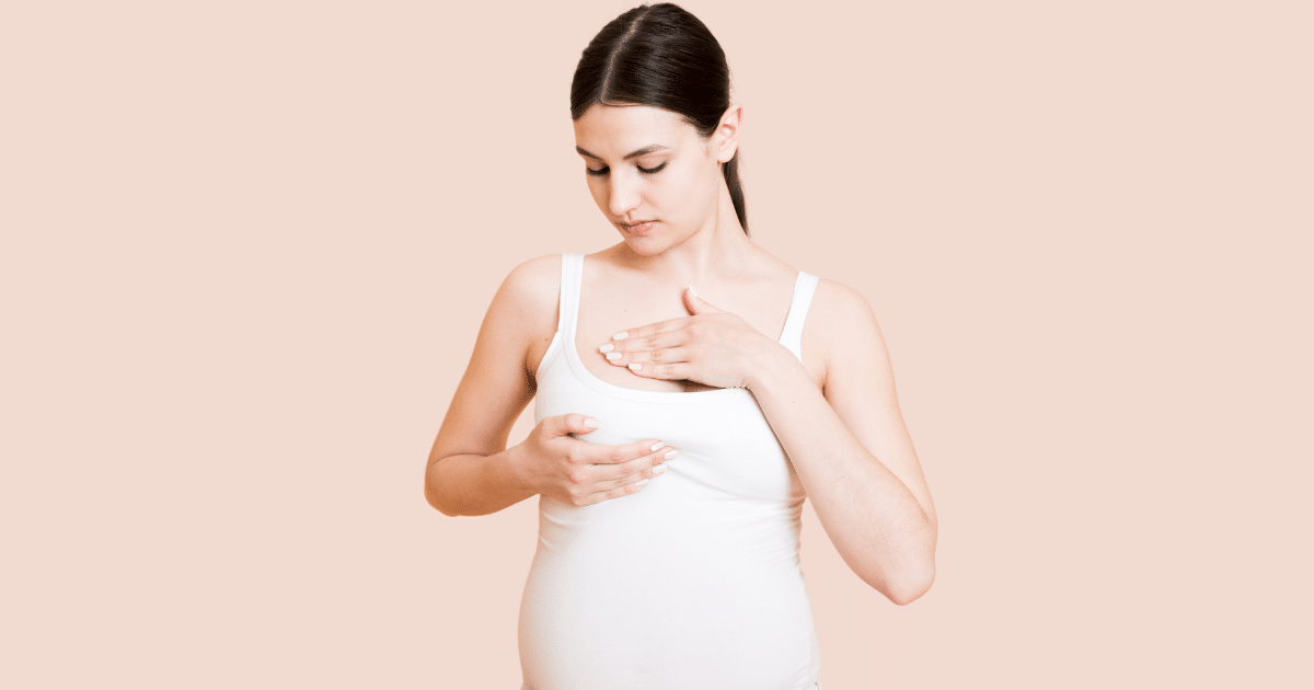 A pregnant woman use her two hands to touch her right breast.