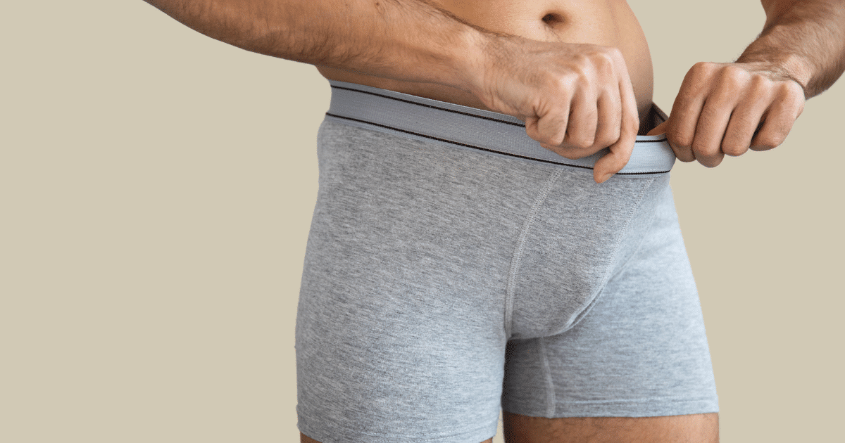 Man in a boxer shorts staring at his penis.